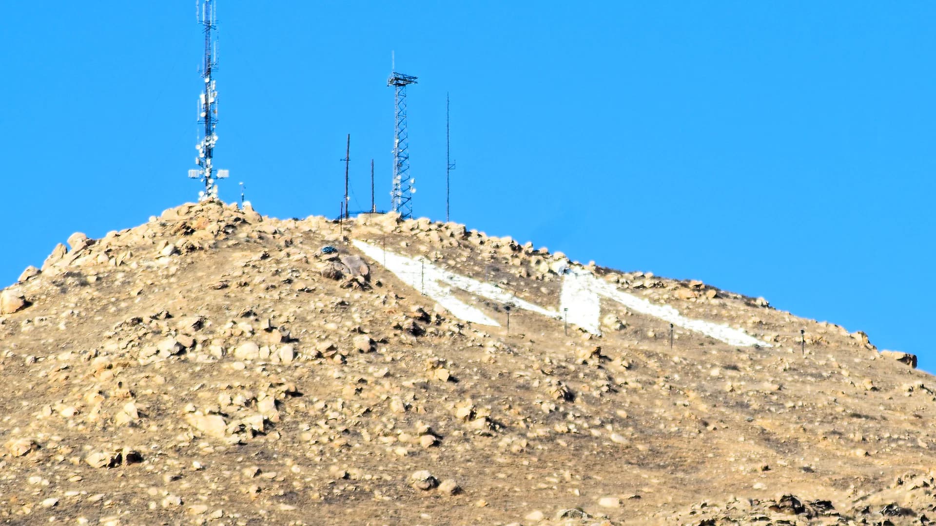 The summit of Box Springs Mountain above Moreno Valley, the whitewashed concrete M laid across the slope below the ridge line and the broadcast towers standing on the peak