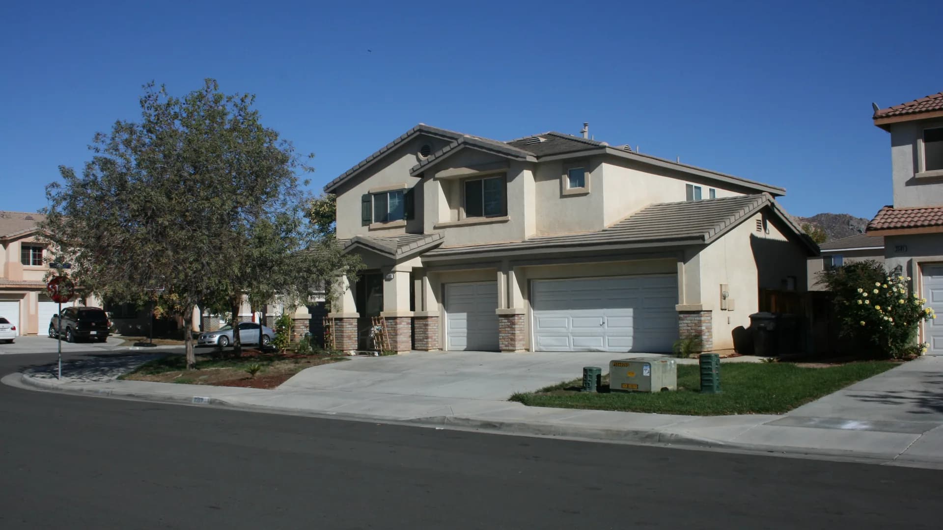 Two-story stucco homes on a corner lot in a Moreno Valley subdivision, hills rising behind the neighborhood