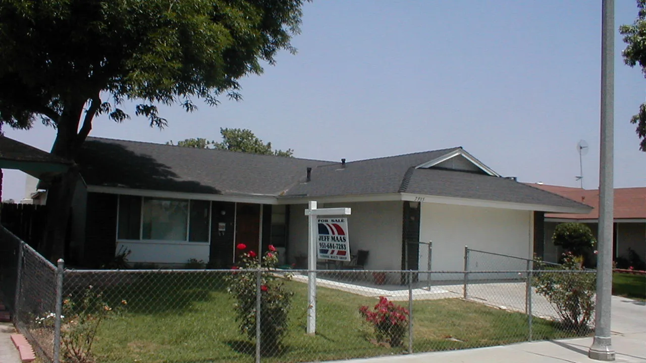 Single-story home behind a chain-link fence with rose bushes in the front yard, the kind of entry-level property VA buyers often purchase