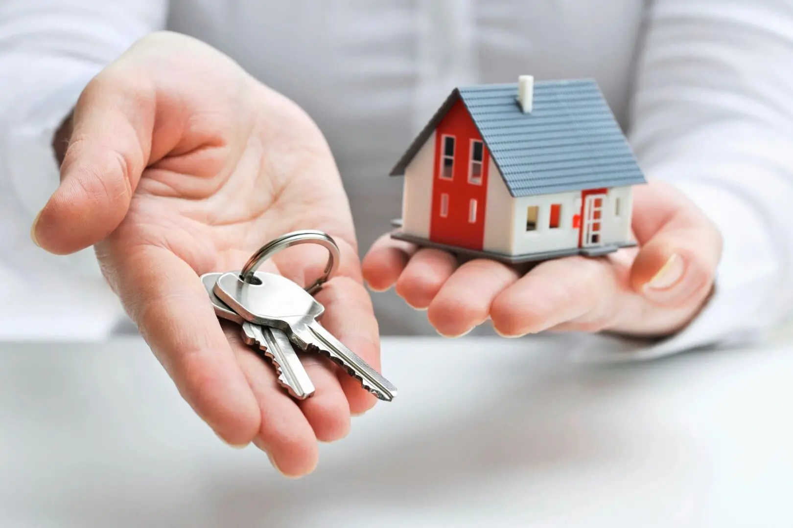 Man is standing with a small house and keys in his hands