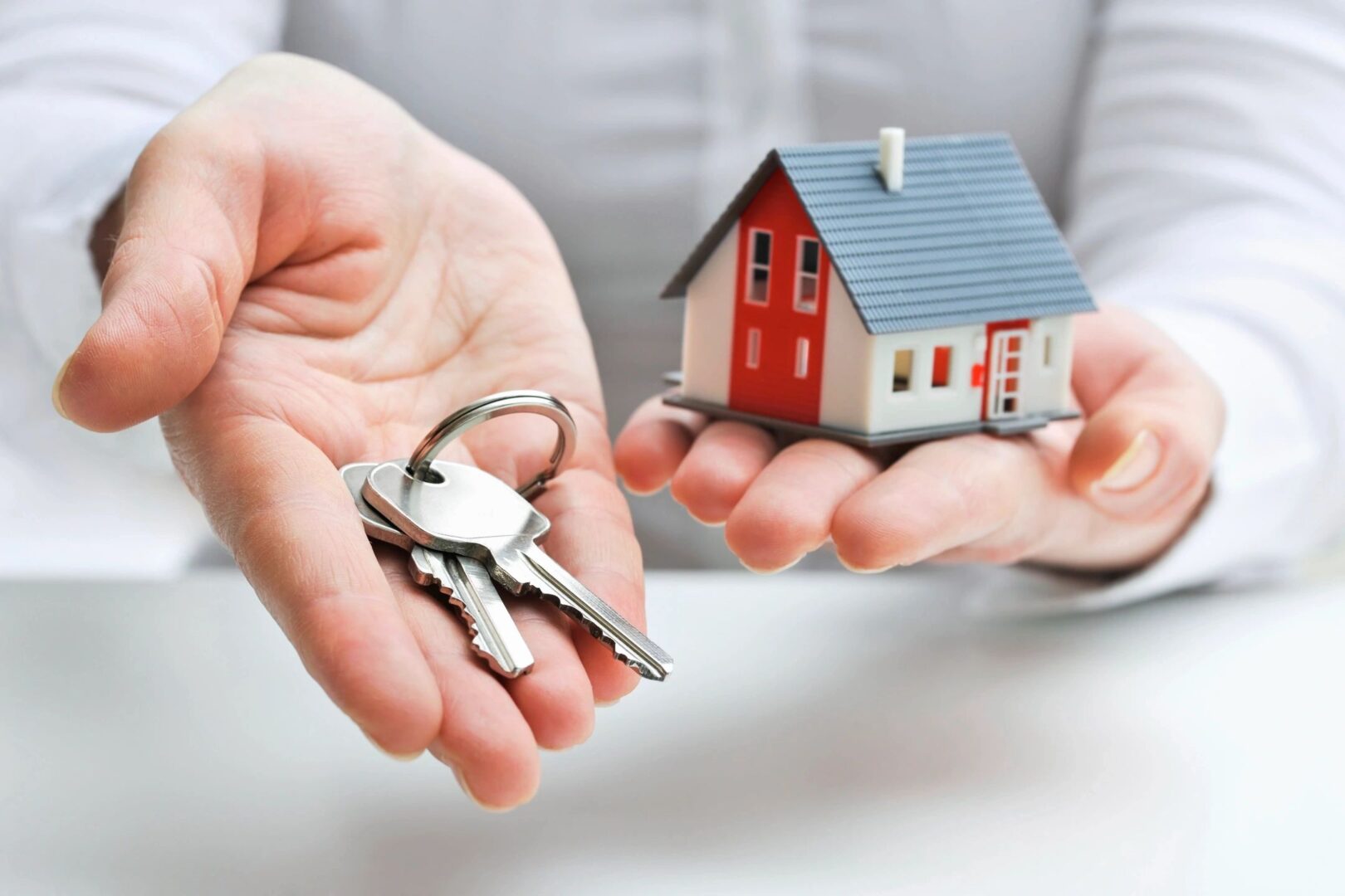 Man is standing with a small house and keys in his hands